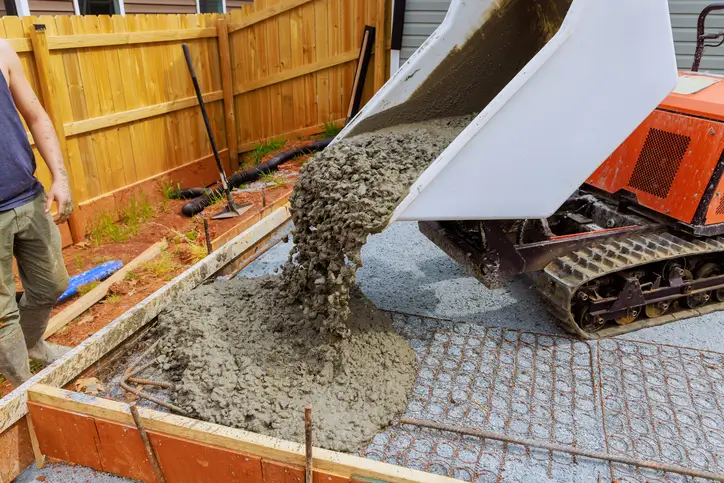 Concrete being poured from a wheelbarrow onto a residential foundation base